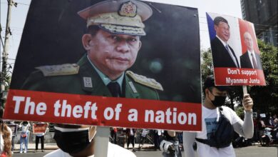 Protesters hold placards depicting Min Aung Hlaing during an anti-coup demonstration in Yangon in February 2021 (EPA)